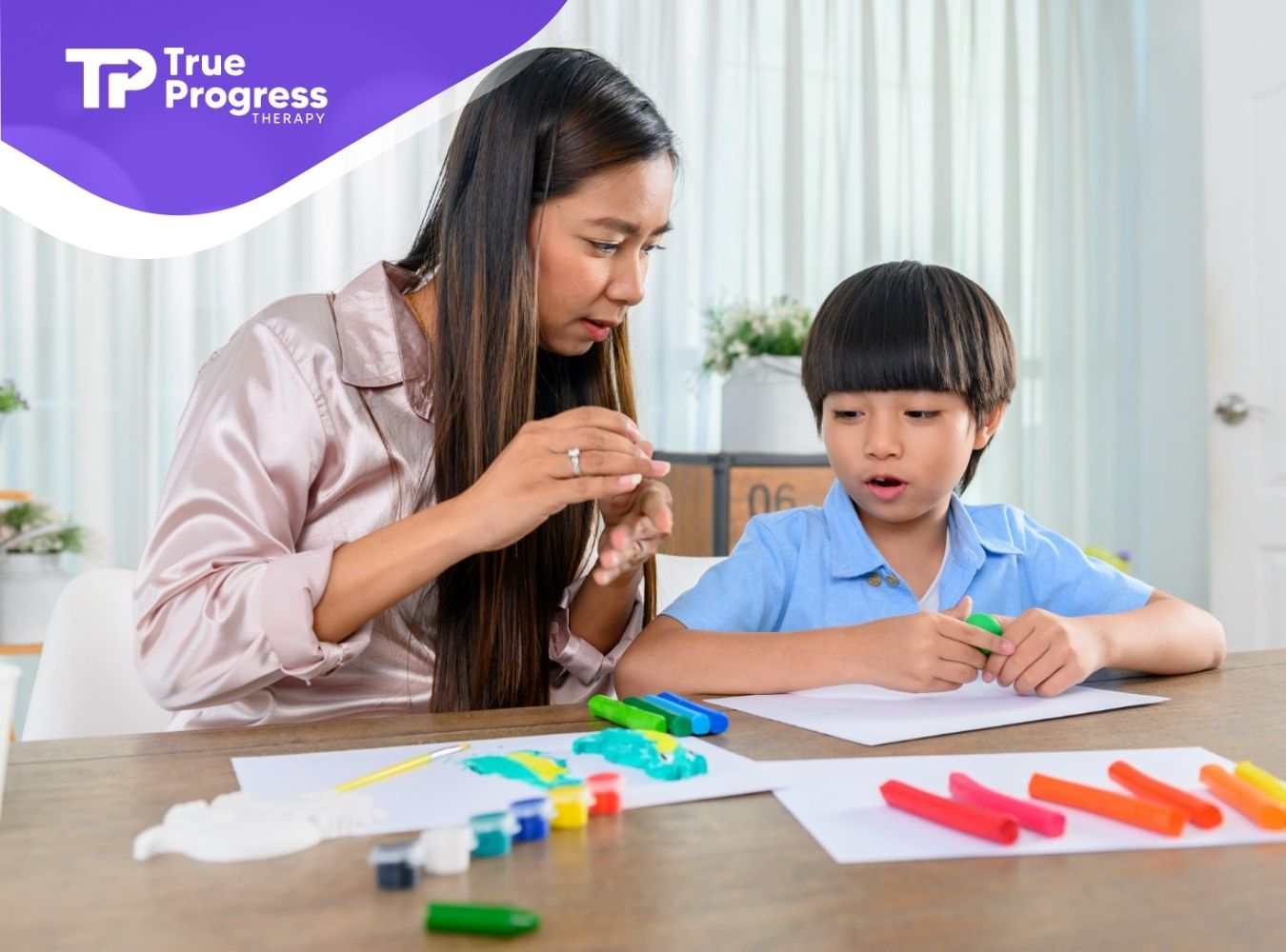 ABA therapist helping a young boy with a hands-on learning activity using colorful clay.